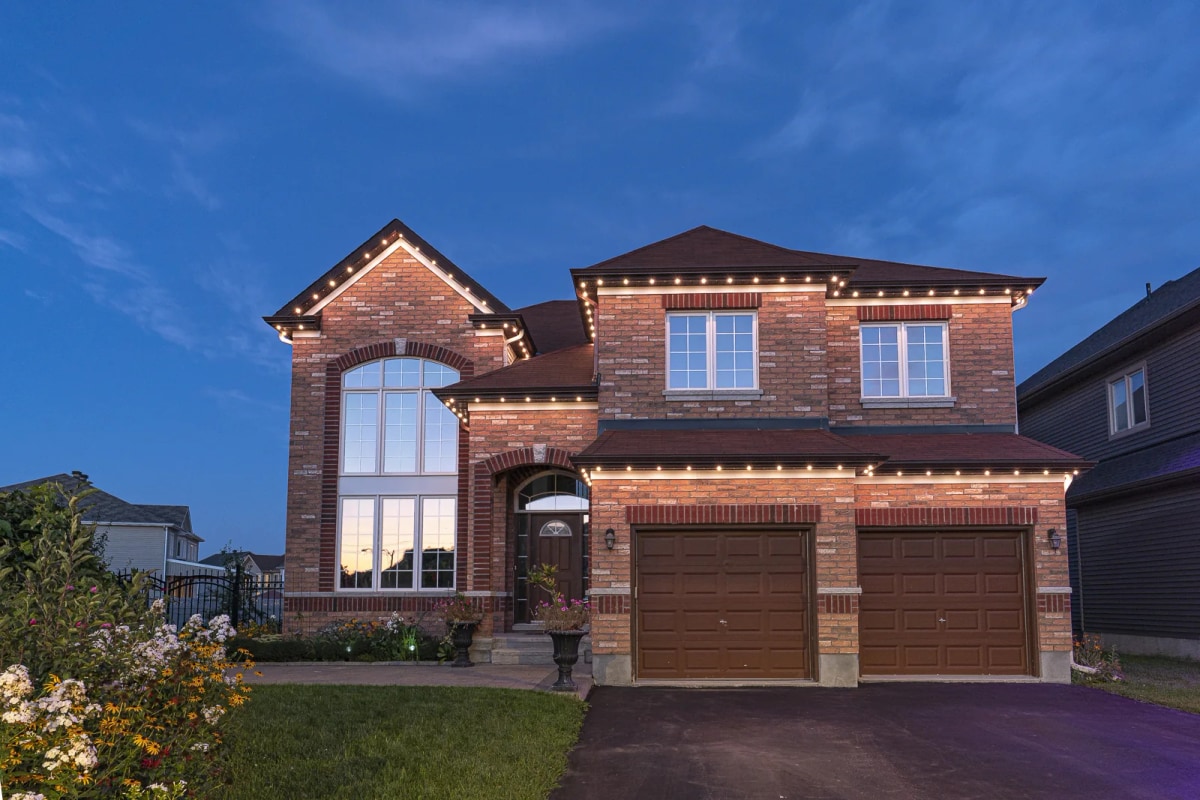 Brick home at dusk with warm white permanent roofline lights
